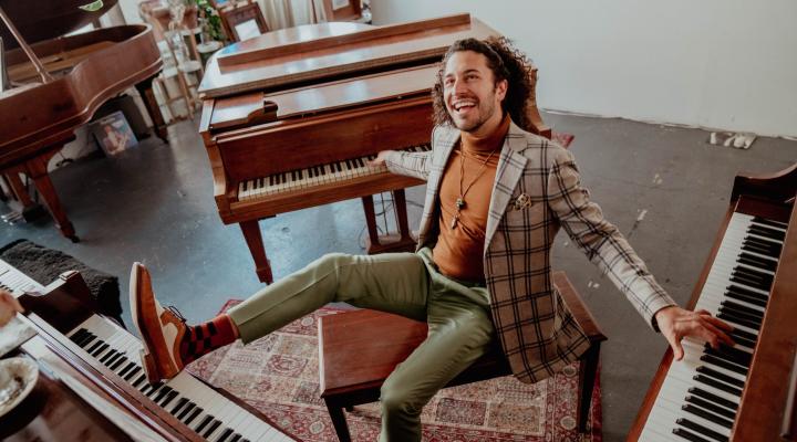 Emmet Cohan surrounded by three pianos