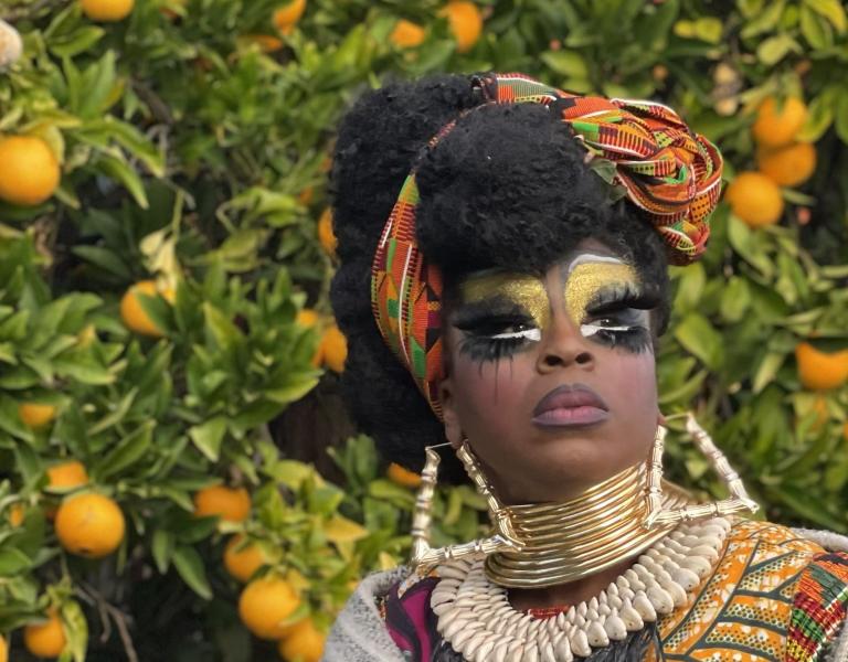 Black Benatar posed in front of an orange tree